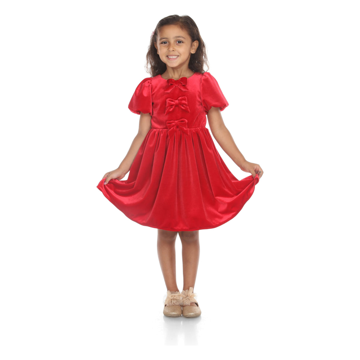 Model holding out the skirt of the red velvet dress with three bows down the front and puffed sleeves