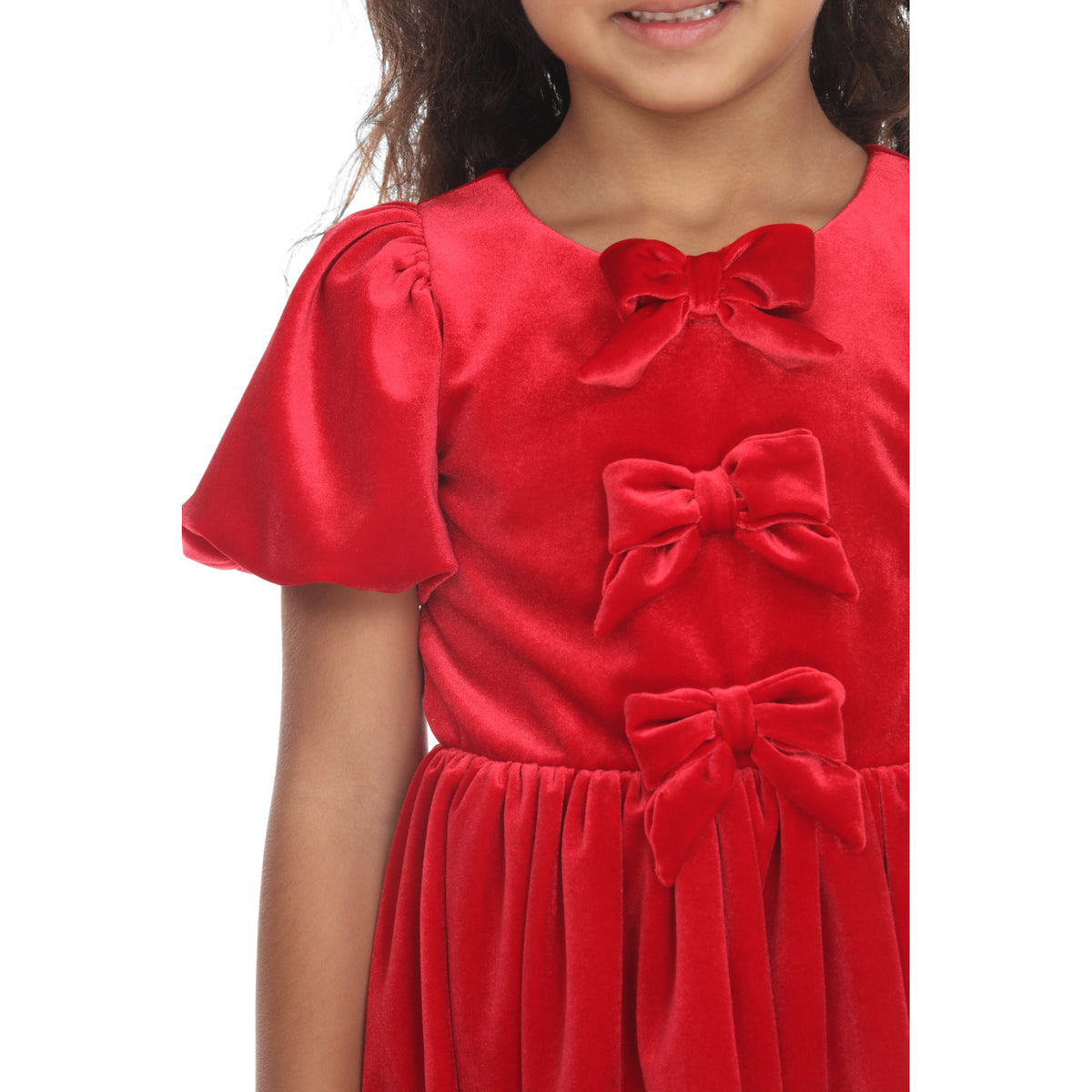 Close-up of the red velvet dress showing three velvet bows down the bodice and a puffed sleeve