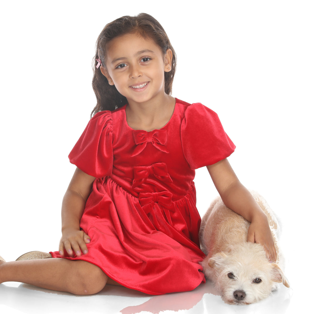 Model sitting with a small dog, wearing the red velvet dress with three bows and puffed sleeves